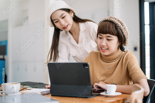 Two young asian woman talking and working together at office.