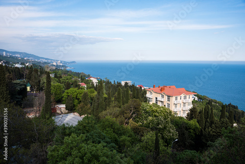 View of the slope of the mountain covered with forest and buildings of the city of Alupka on the Crimean Peninsula against the Black Sea