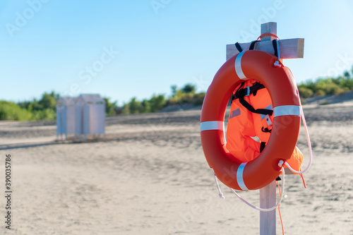 Bright lifebuoy and life jacket on the beach