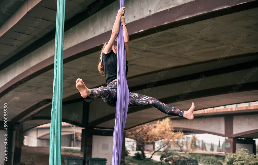 Φωτογραφία Young Caucasian woman doing aerial yoga with hammocks in the park