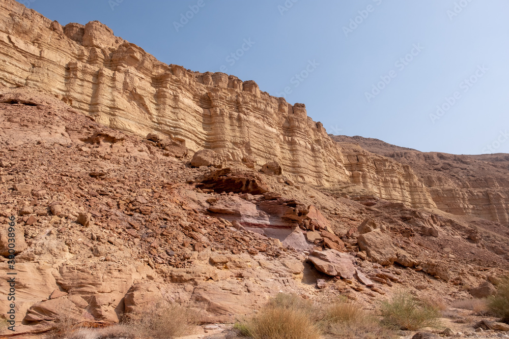 Fototapeta premium Hiking trail in wadi Zafit, Negev desert, Israel. Desert landscape with limestone mountains, sandy hills, rock formations and huge boulders.