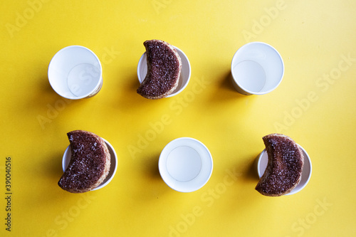 A number of semilunar candied cookies and cardboard cups organized on a bright yellow background photo