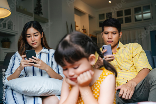 Asian little girl being ignore by her parents at home. photo