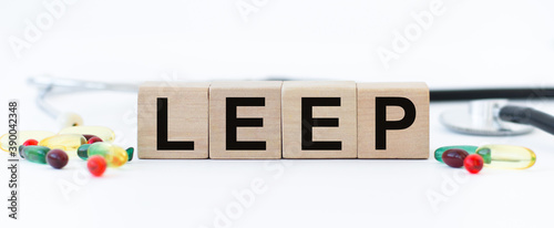 cubes with the word LEEP on them are scattered pills and a stethoscope. Isolated on a white background. Care concept. photo