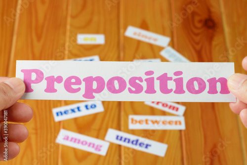 hand holding English preposition card over blurred preposition words photo