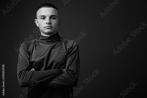 Studio shot of young handsome man with short hair against gray background