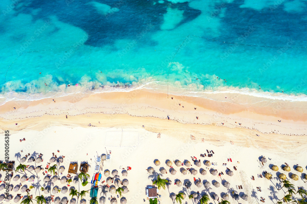 Beach vacation and travel background. Aerial drone view of beautiful atlantic tropical beach with straw umbrellas, palms and boats. Bavaro beach, Punta Cana, Dominican Republic. Beach vacation and travel background. Aerial drone view of beautiful atlantic tropical beach with straw umbrellas, palms and boats. Bavaro beach, Punta Cana, Dominican Republic.