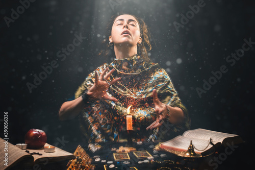 Astrology, magic and divination. The sorceress creates the magic of divination over a candle. Black background. There are magic items on the table photo