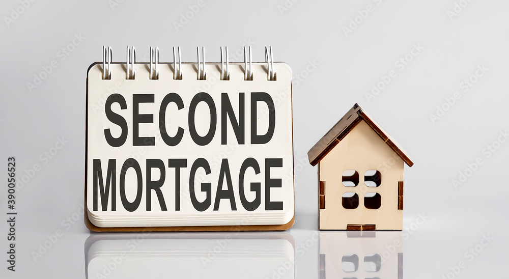 second mortgage words written in an office notebook with wooden house. Financial Business concept. second mortgage words written in an office notebook with wooden house. Financial Business concept.