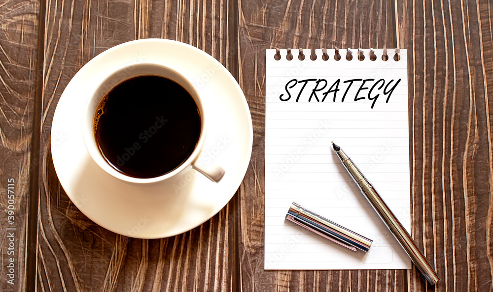 STRATEGY - white paper with pen and coffee on wooden background STRATEGY - white paper with pen and coffee on wooden background