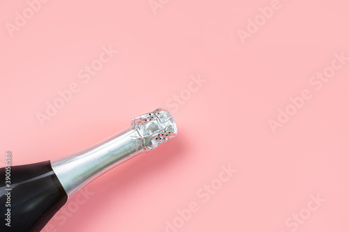 Neck of a champagne bottle with silver foil on a pastel pink background. The concept of a celebration, holiday, new year. Minimalism, copy space.