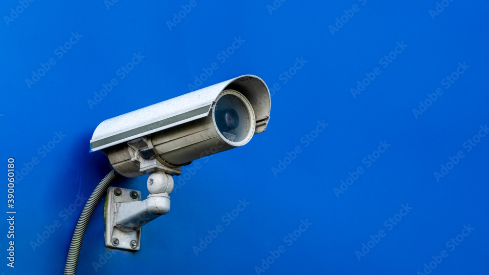 A security camera on blue wall