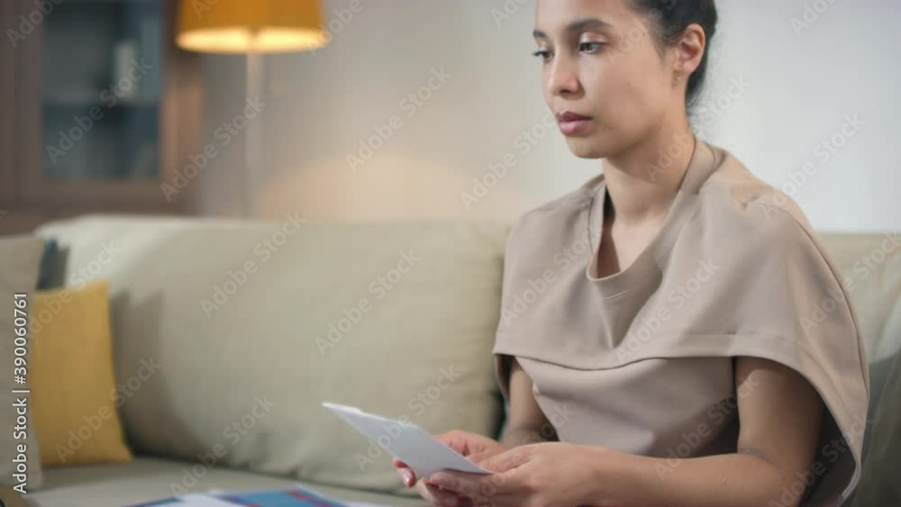 Mixed race woman doing paperwork getting bad news looking frustrated thinking of money debt, budget loss, bankruptcy sitting at home office desk Mixed race woman doing paperwork getting bad news looking frustrated thinking of money debt, budget loss, bankruptcy sitting at home office desk