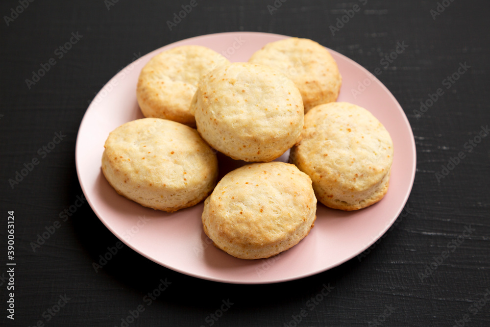 Homemade Flaky Buttermilk Biscuits on a pink plate on a black background, side view. Close-up.