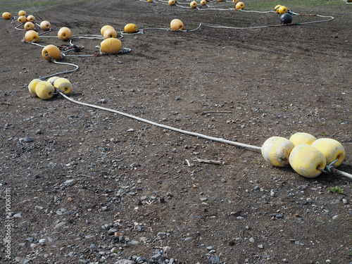 Yellow buoys and beacons on seaside harbour in fishing village on cloudy day on Hokkaido island, northern Japan