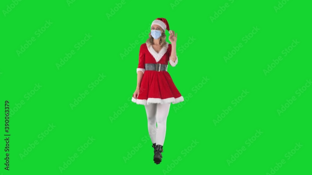 Happy Santa Claus helper girl walking and greeting remove covid-19 face mask to reveal face. Full body length on green screen background. Happy Santa Claus helper girl walking and greeting remove covid-19 face mask to reveal face. Full body length on green screen background.