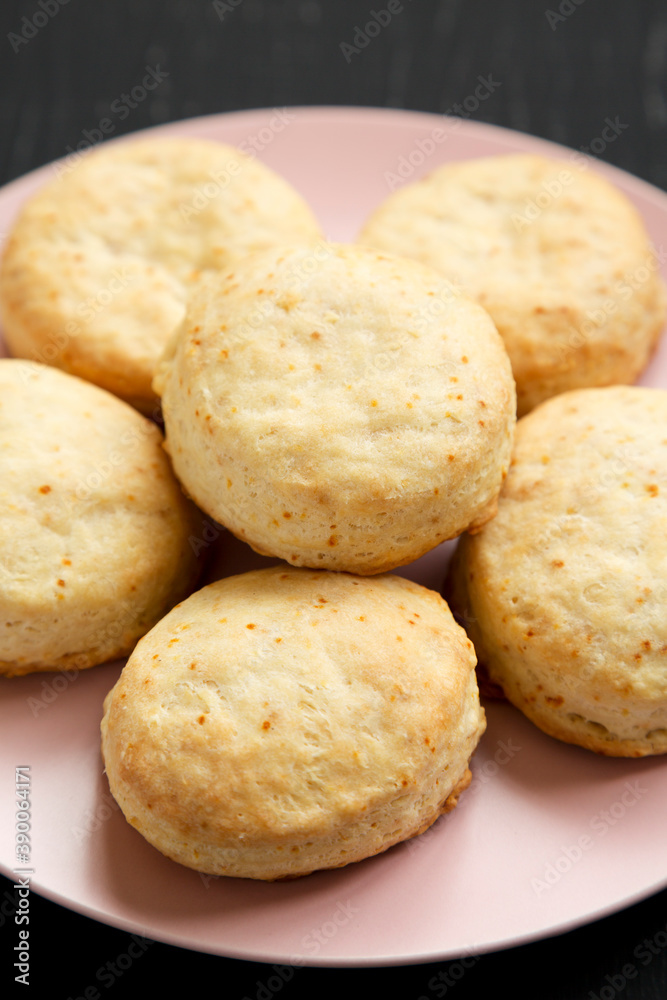 Homemade Flaky Buttermilk Biscuits on a pink plate on a black background, low angle view. Close-up.