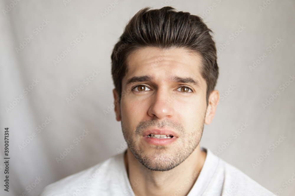 Portrait of a young handsome man with a slight pain face expression and a question in his eyes Portrait of a young handsome man with a slight pain face expression and a question in his eyes