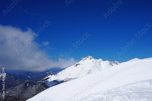 Beautiful winter landscape in the mountains, deep snow, blue sky, ski slopes, winter forest, snow-capped mountain peaks. © Михаил Рафибеков