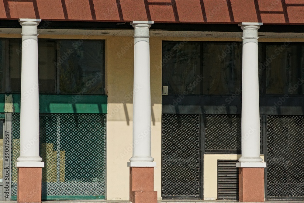 Naklejka premium a row of white concrete columns against a gray metal mesh wall on a city street on a sunny day