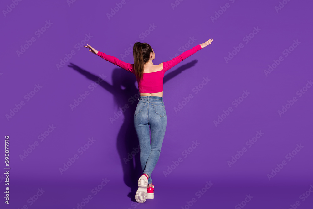 Full length body size rear back behind view of attractive slender girl going enjoying leisure isolated over bright violet color background Full length body size rear back behind view of attractive slender girl going enjoying leisure isolated over bright violet color background