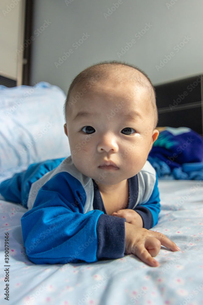Adorable baby boy during tummy time on bed. Newborn child relaxing in bed Adorable baby boy during tummy time on bed. Newborn child relaxing in bed
