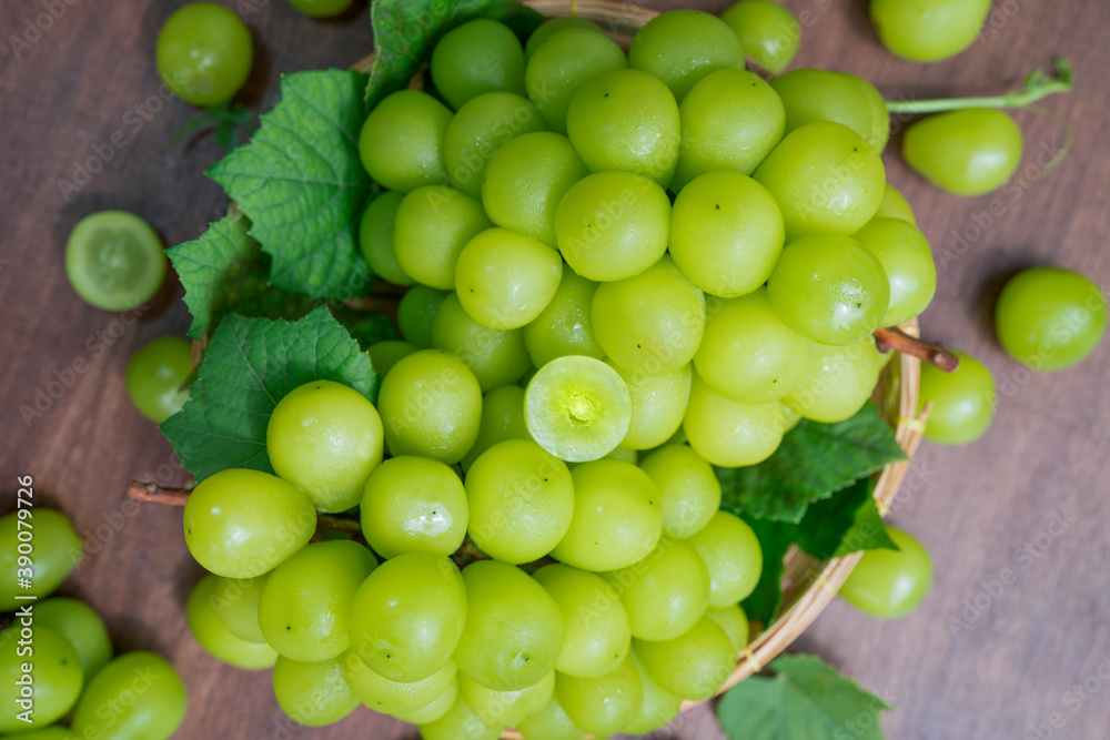 Shine Muscat Grape with leaves in wooden background, Green grape in Bamboo basket on wooden table in garden. Shine Muscat Grape with leaves in wooden background, Green grape in Bamboo basket on wooden table in garden.