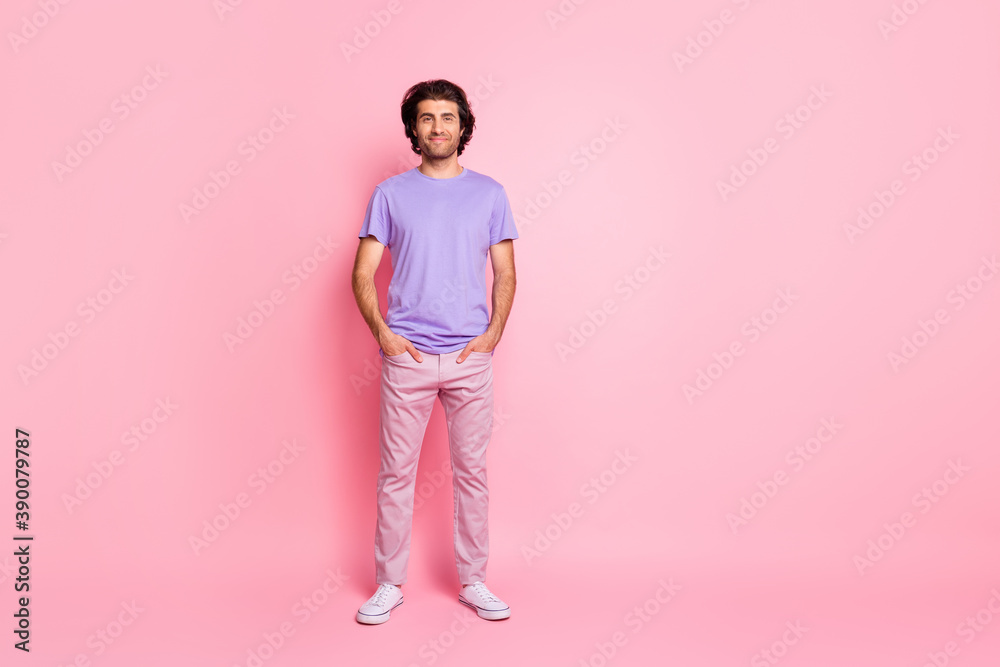 Full length photo of charming bearded guy hands pockets wear violet shirt pants sneakers isolated pastel pink color background Full length photo of charming bearded guy hands pockets wear violet shirt pants sneakers isolated pastel pink color background