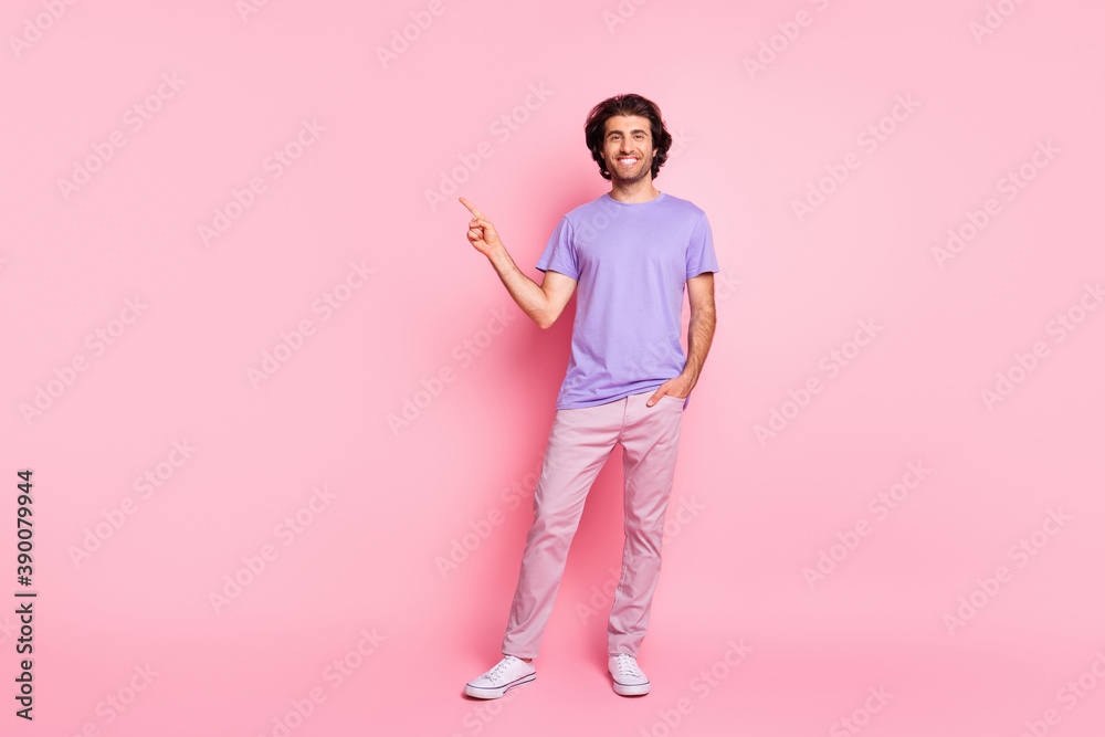 Full length photo of guy direct finger empty space palm pocket wear violet shirt pants footwear isolated pastel pink color background Full length photo of guy direct finger empty space palm pocket wear violet shirt pants footwear isolated pastel pink color background