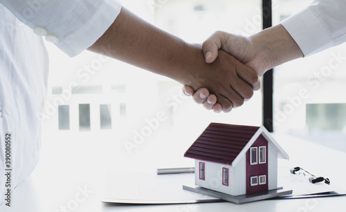 Home salespeople congratulate customers who have bought a home by shaking hands.