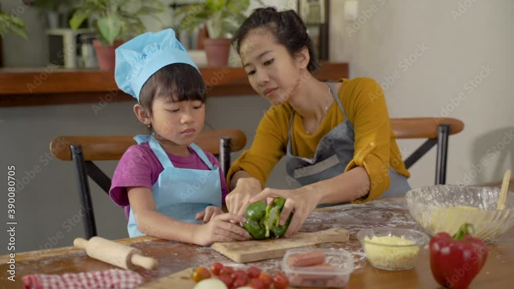 mother teach her daughter on how to cut a paprika to make a pizza
