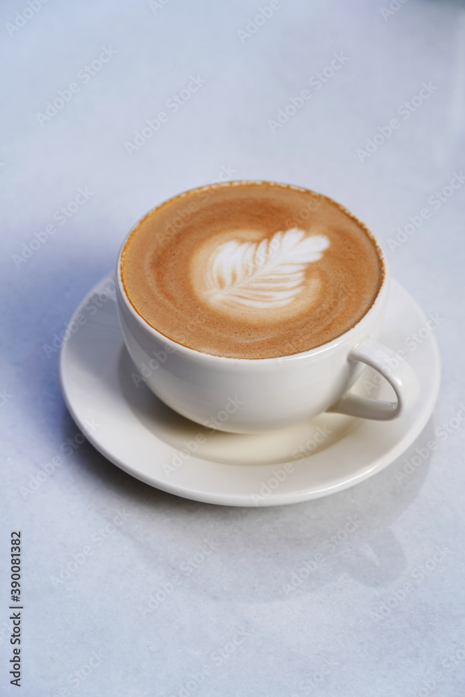 Fototapeta Cappuccino coffee cup on white table. Latte art coffee