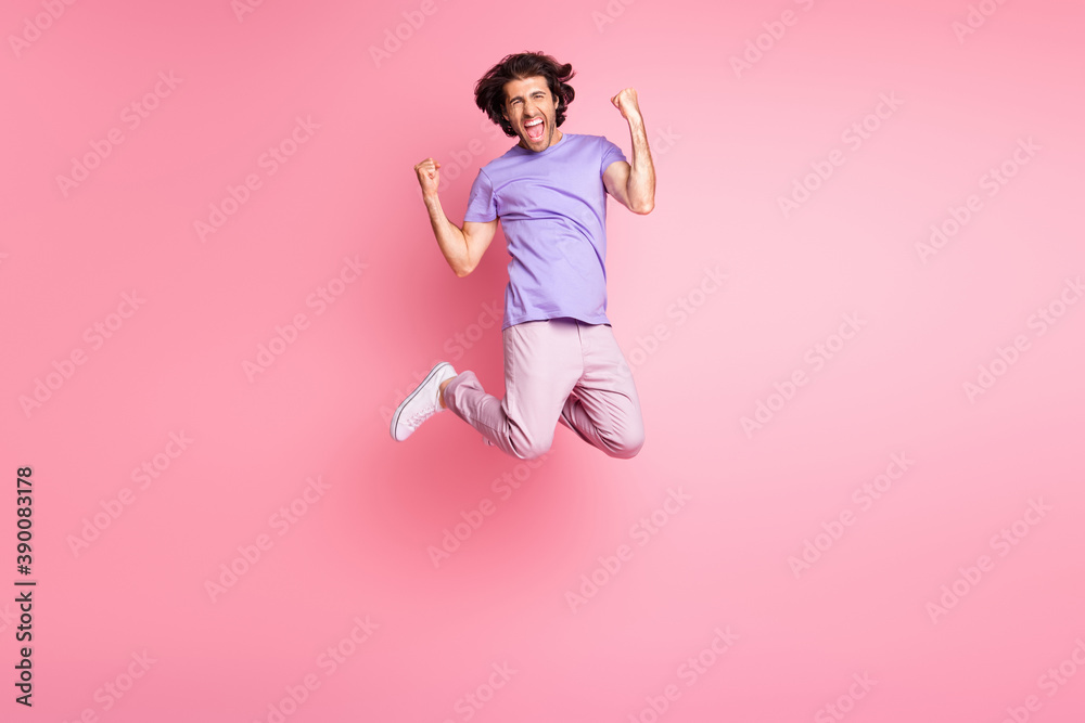 Full size photo of astonished brown haired young man scream yes lucky win raise fists jump up wear pink pants isolated on pink color background Full size photo of astonished brown haired young man scream yes lucky win raise fists jump up wear pink pants isolated on pink color background