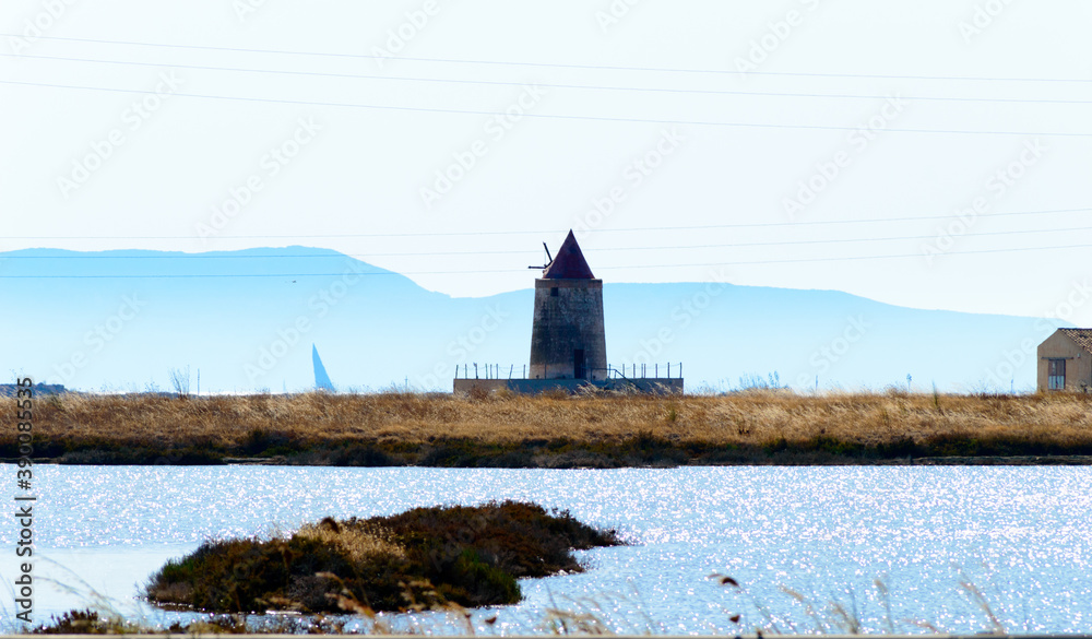 Landscape view of the salt Pans of Trapani in Sicily with colorful waters, white salt piles and red wind mill