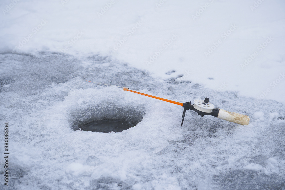 Naklejka premium Winter fishing rod at the drilled hole catches fish. Ice fishing
