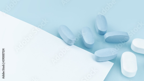 Medical background of many white and blue capsule tablets or pills on the table. Close up notice copy space. Healthcare pharmacy and medicine concept. Painkillers or prescription drugs consumption photo