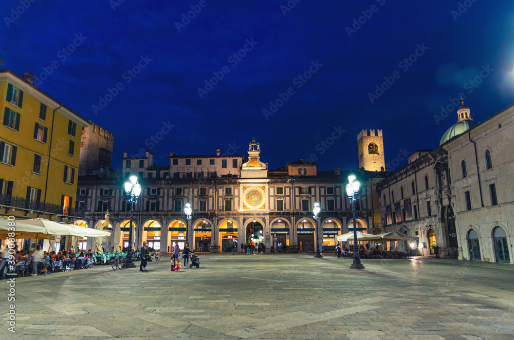 Torre dell'Orologio tower Renaissance style building with astronomical clock, street lights in Piazza della Loggia Square, Brescia city historical centre, night evening view, Lombardy, Northern Italy