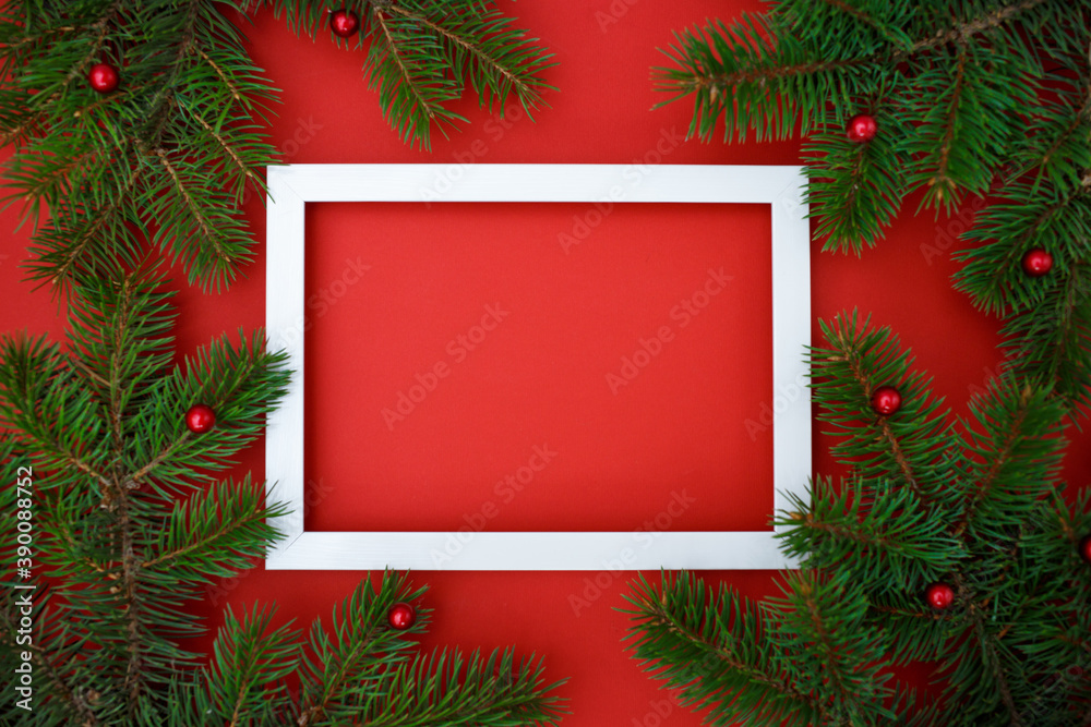 Creative layout made of Christmas tree branches with frame on red background. Flat lay. Nature New Year concept. Creative layout made of Christmas tree branches with frame on red background. Flat lay. Nature New Year concept.