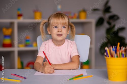 Cute little child girl writing with pencils in day care center