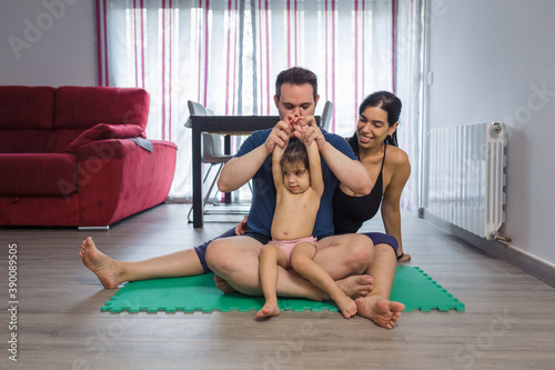 family of 3 are sitting on yoga mats, sports dresses, portrait photo.