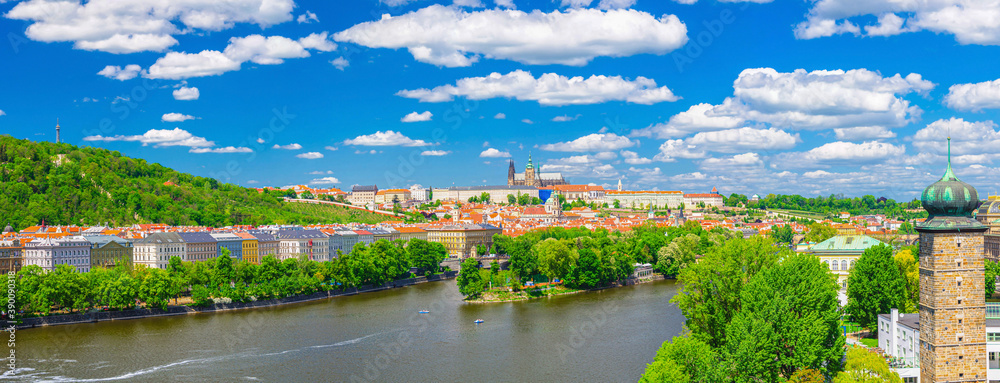 Panorama of Prague city historical centre with Prague Castle, St. Vitus Cathedral, Hradcany district, green hills and Vltava river, blue sky. Aerial panoramic view of Prague city, Czech Republic