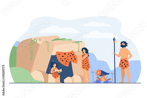 Prehistoric family couple and kid wearing leopard hides, cooking food at cave entrance. Vector illustration for ancient people stone age, caveman dinner concept