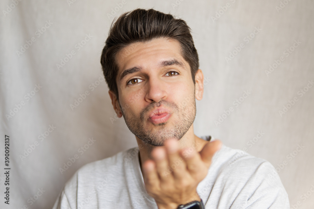 Portrait of a young beautiful man sending a kiss with his lips and hand gesture Portrait of a young beautiful man sending a kiss with his lips and hand gesture