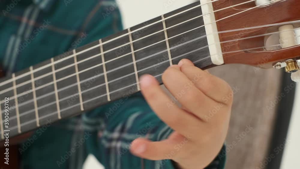 Little boy is playing big classical guitar (hands close-up). Slow motion Little boy is playing big classical guitar (hands close-up). Slow motion
