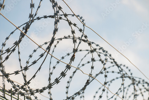 Barbed wire fence on european and world border on blue sky background sunny day, closed borders concept