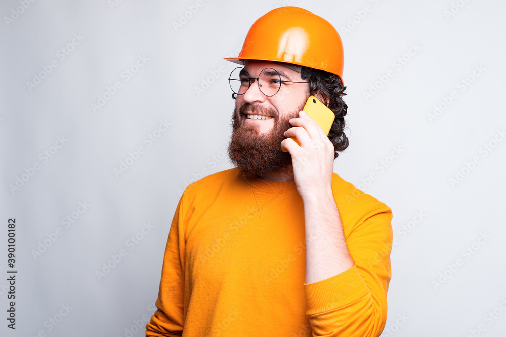 Photo of bearded young architect wearing helmet and talking on phone. Photo of bearded young architect wearing helmet and talking on phone.