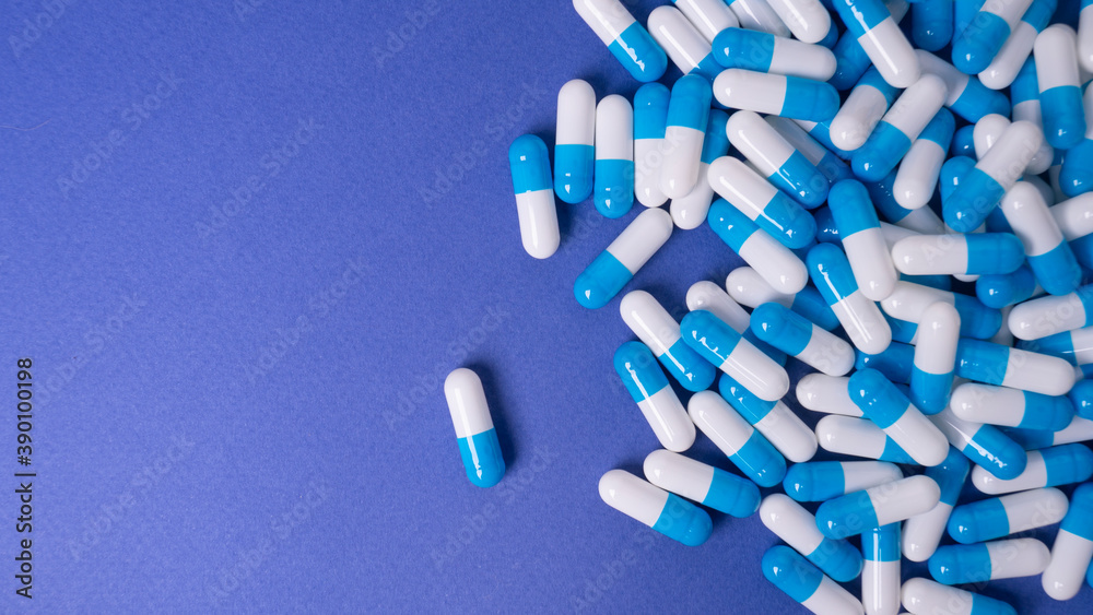 white and blue pills on a blue background. medical background white and blue pills on a blue background. medical background
