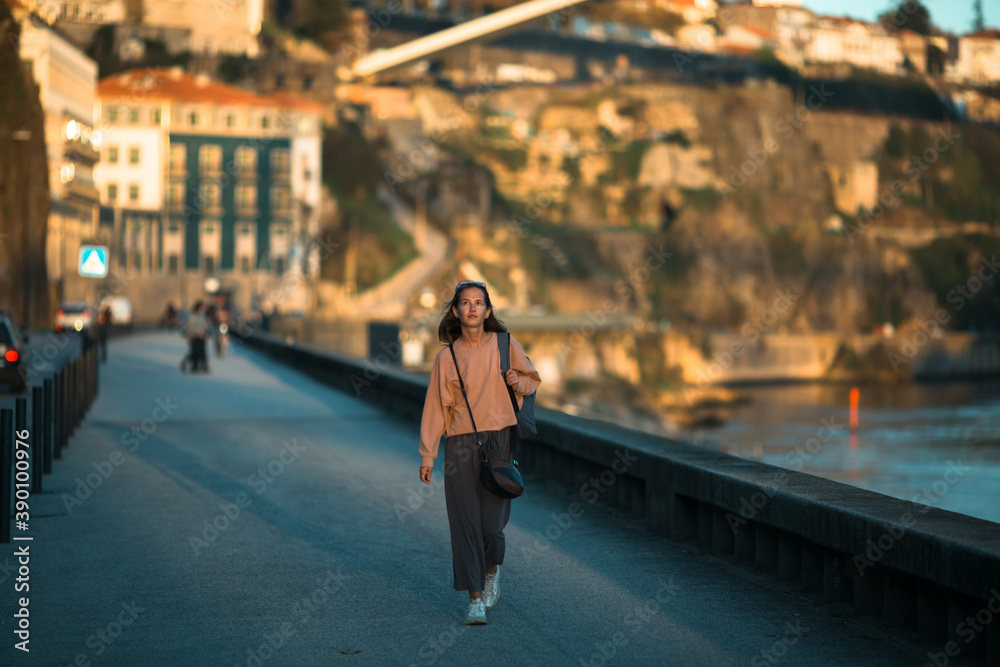 A young woman walks along the city's river embankment. A young woman walks along the city's river embankment.
