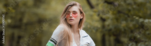 young stylish woman in sunglasses looking away in forest, banner © LIGHTFIELD STUDIOS