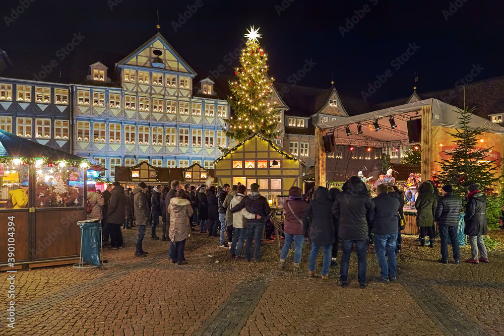 Wolfenbuttel, Germany. Christmas market at Stadtmarkt (Town Market square) in front of Town Hall in night. Unknown people watch a performance of an unidentified musical band from the wooden stage.